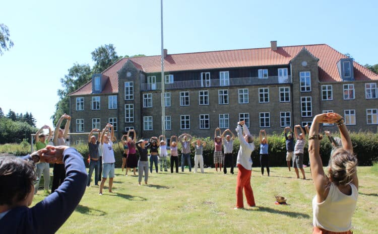 Photo of a group of people exercising in front of Avnø Oasis Ecovillage.